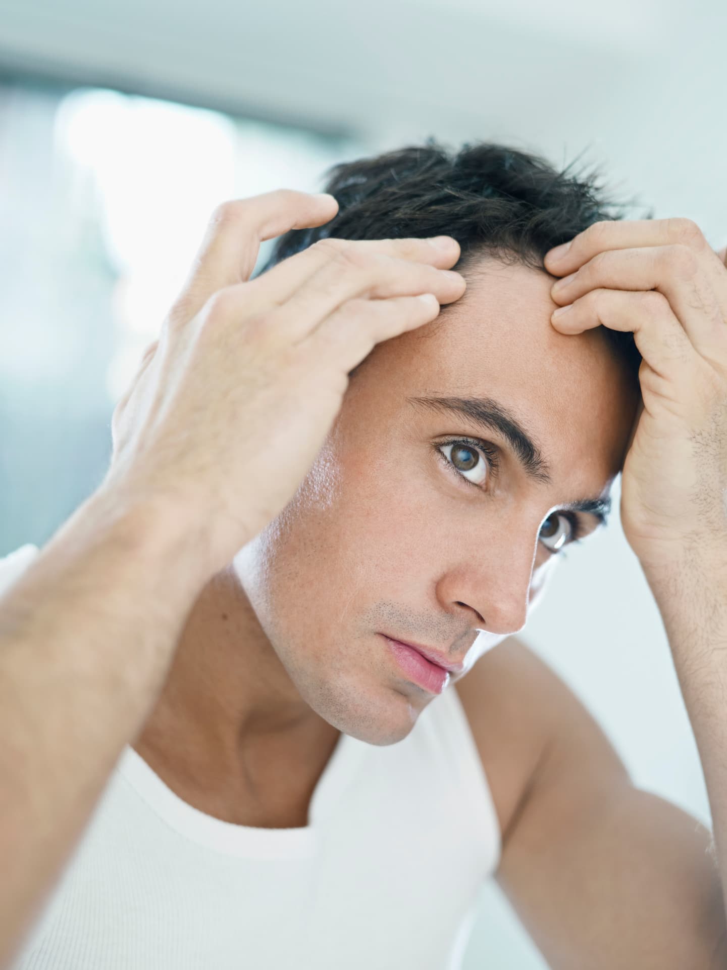 Man checking his hairline in a bright room