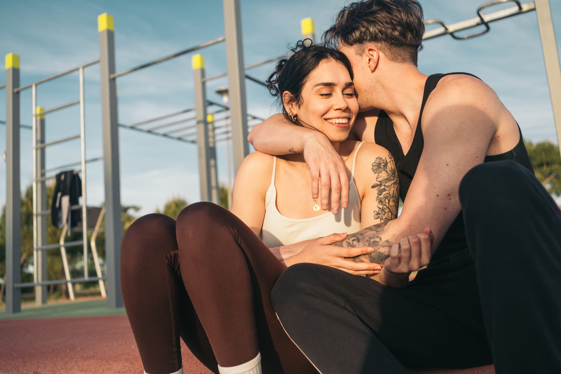 Couple in activewear sitting together outdoors after a workout in warm daylight