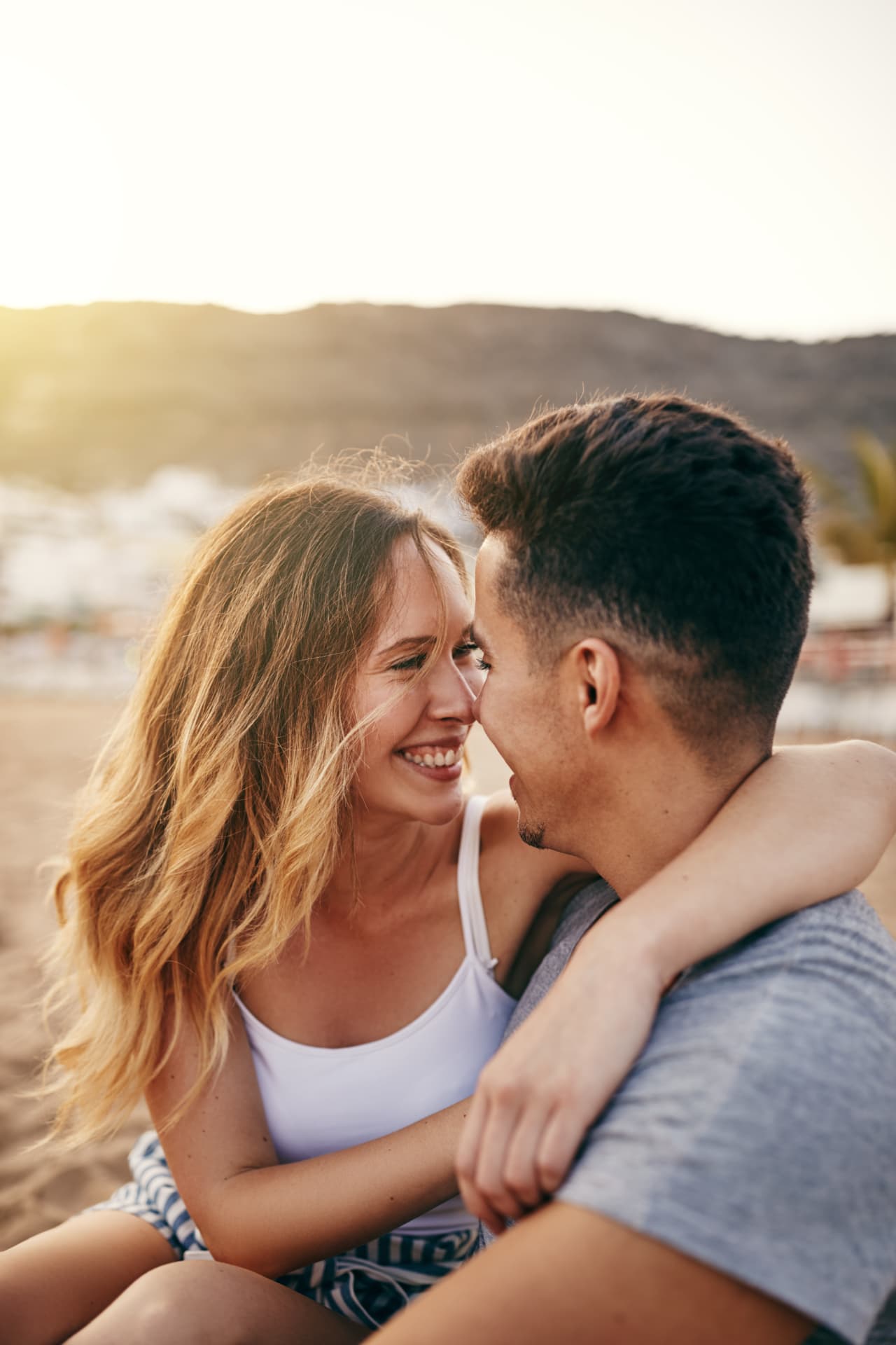 Couple embracing and laughing together on a beach at sunset