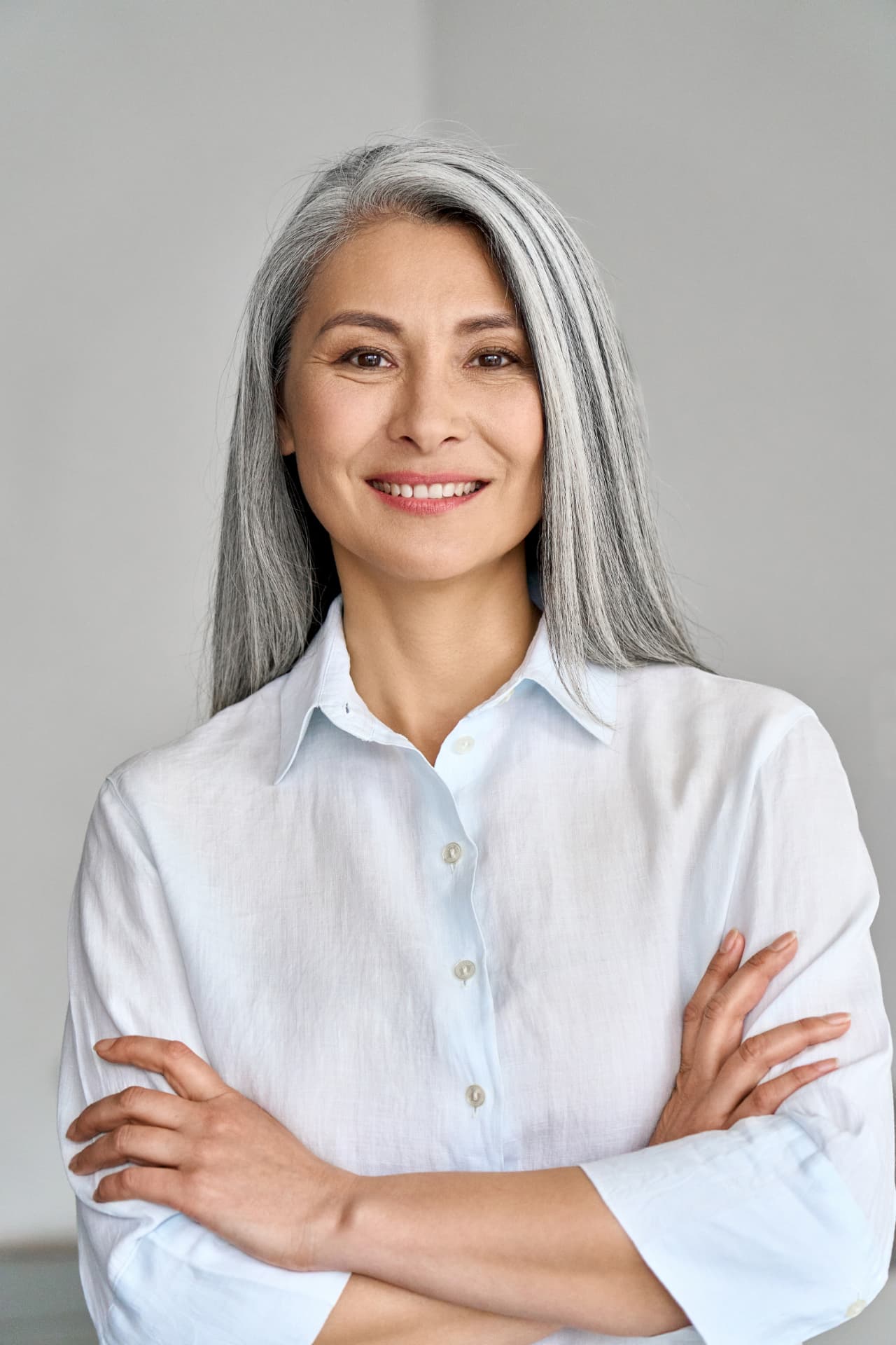 Confident smiling woman with silver hair in a light blue shirt