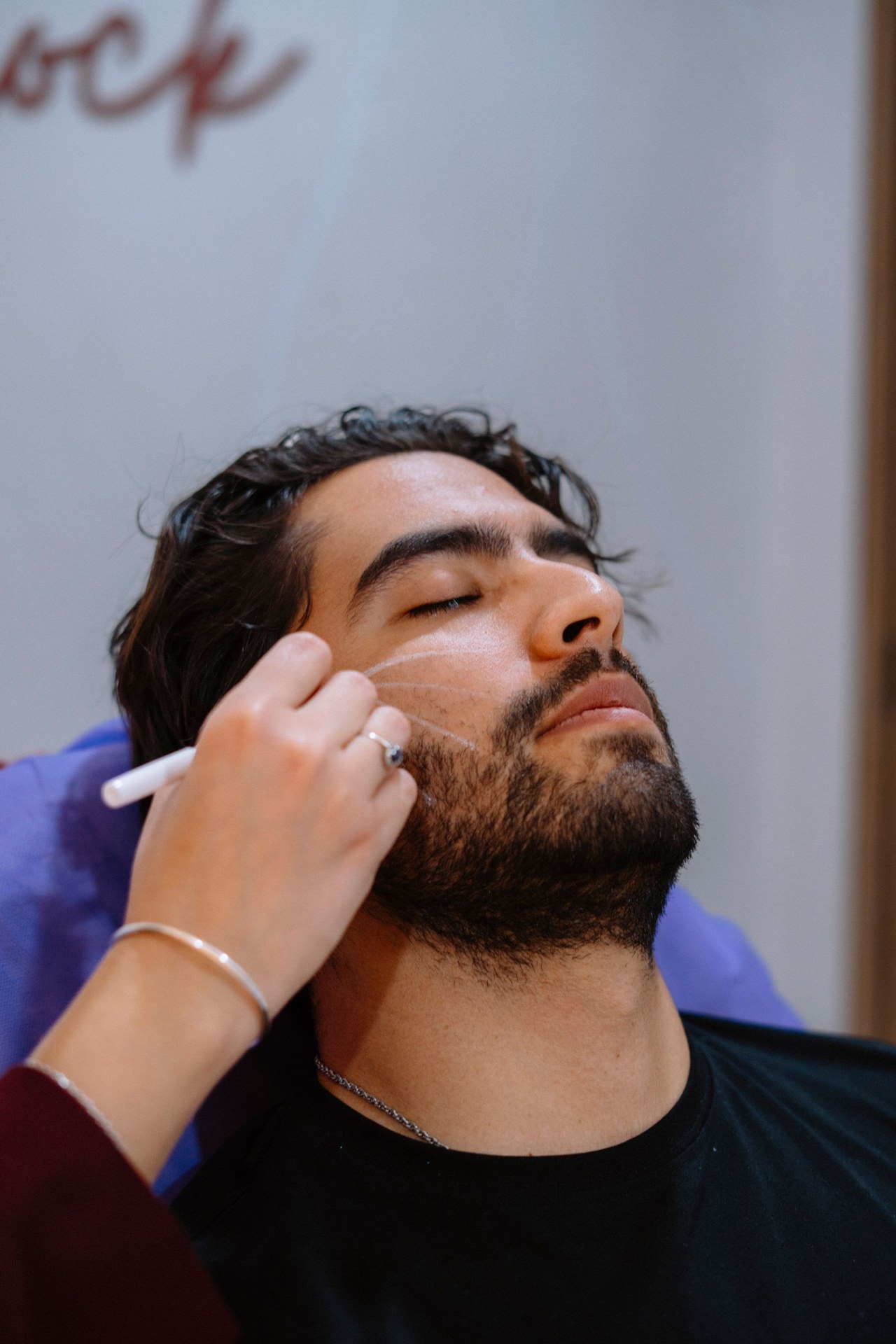 Close-up of a man applying compounded skin cream along his cheek
