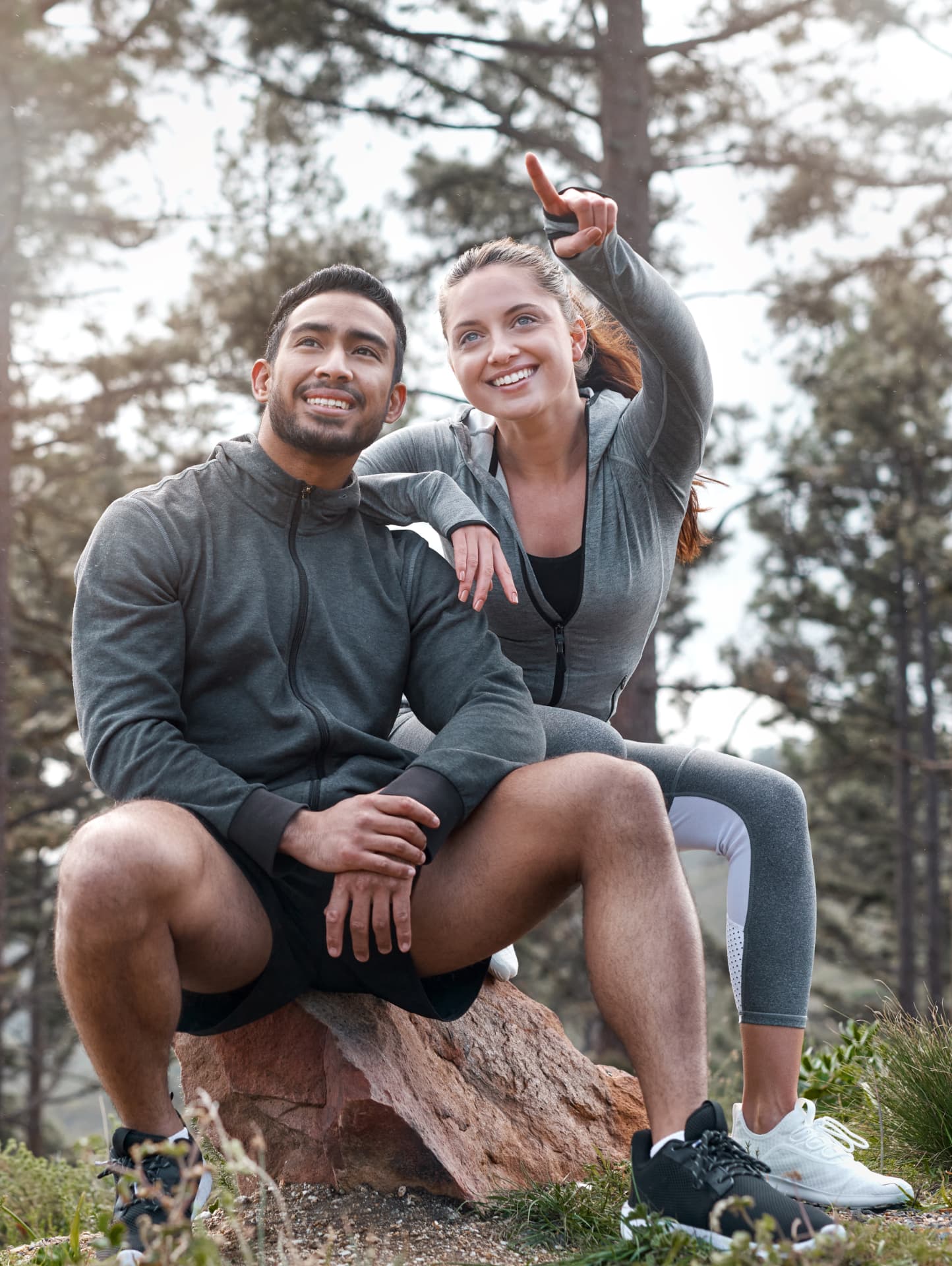 Couple in athletic wear resting on a rock in a forest