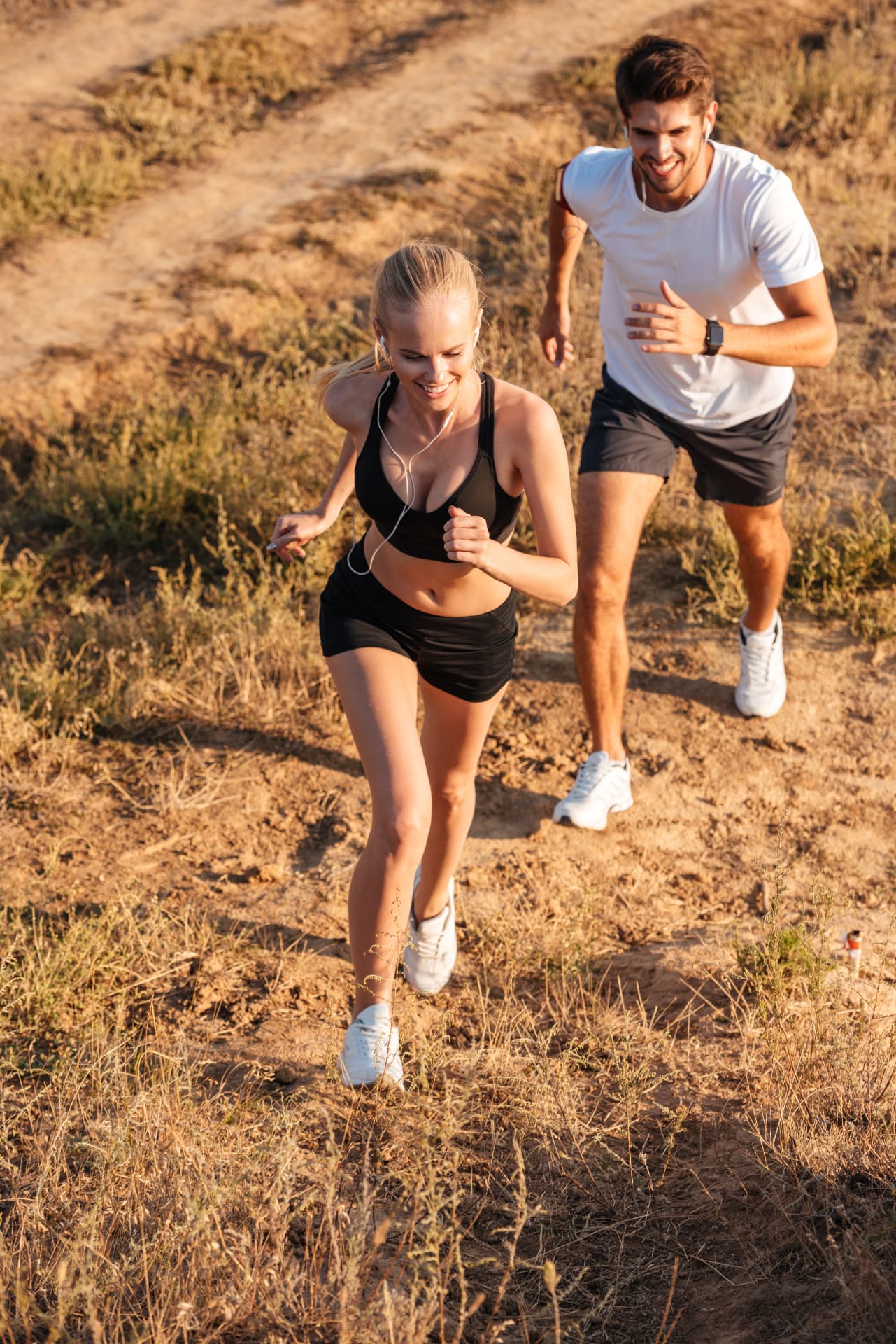 Couple running together on a sunlit trail