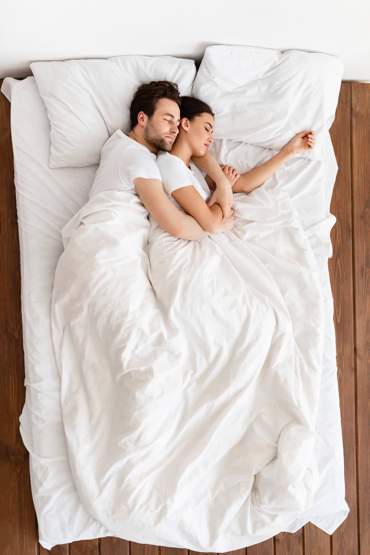 Couple sleeping peacefully together in white bedding