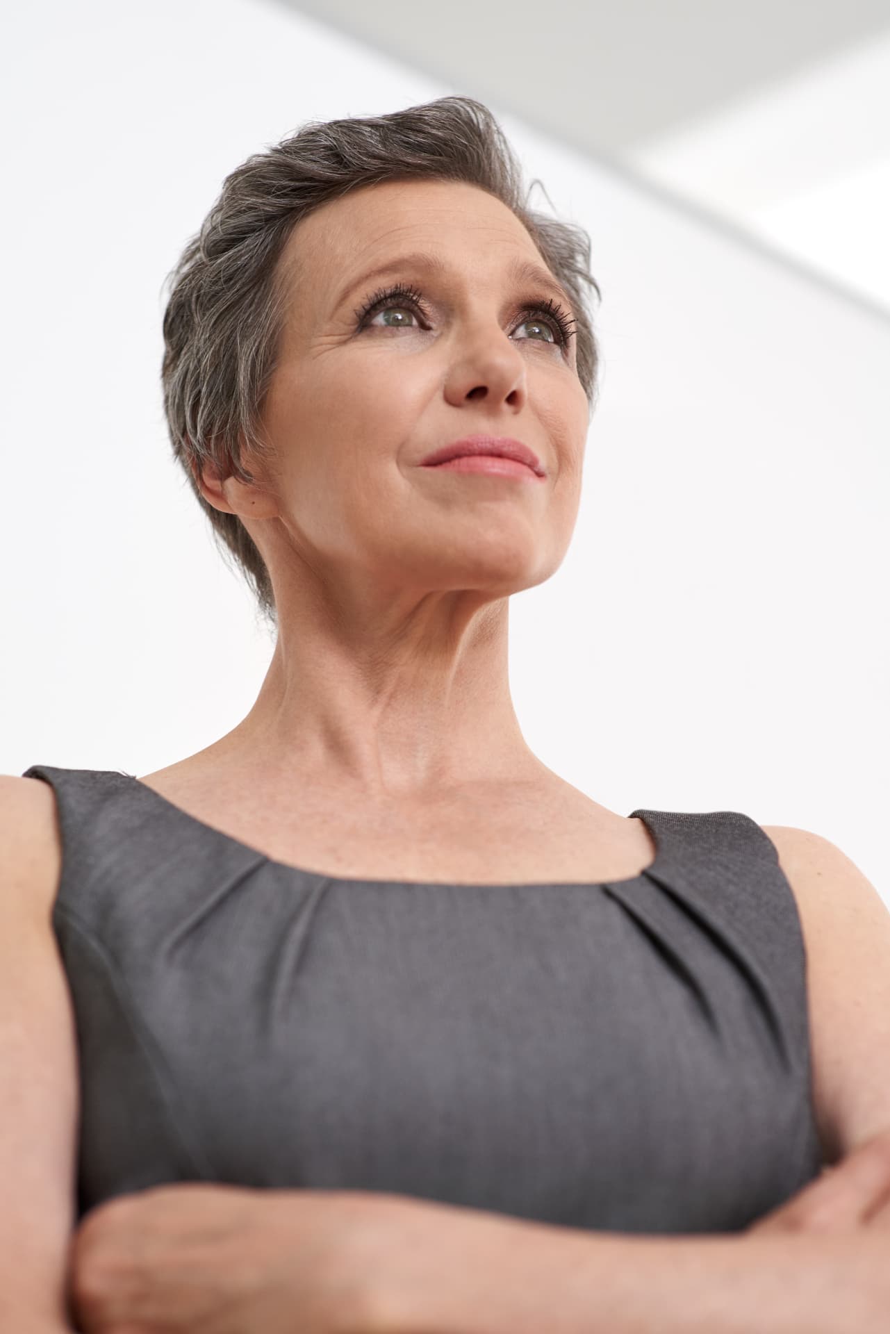 Professional woman in a grey dress looking calmly upward