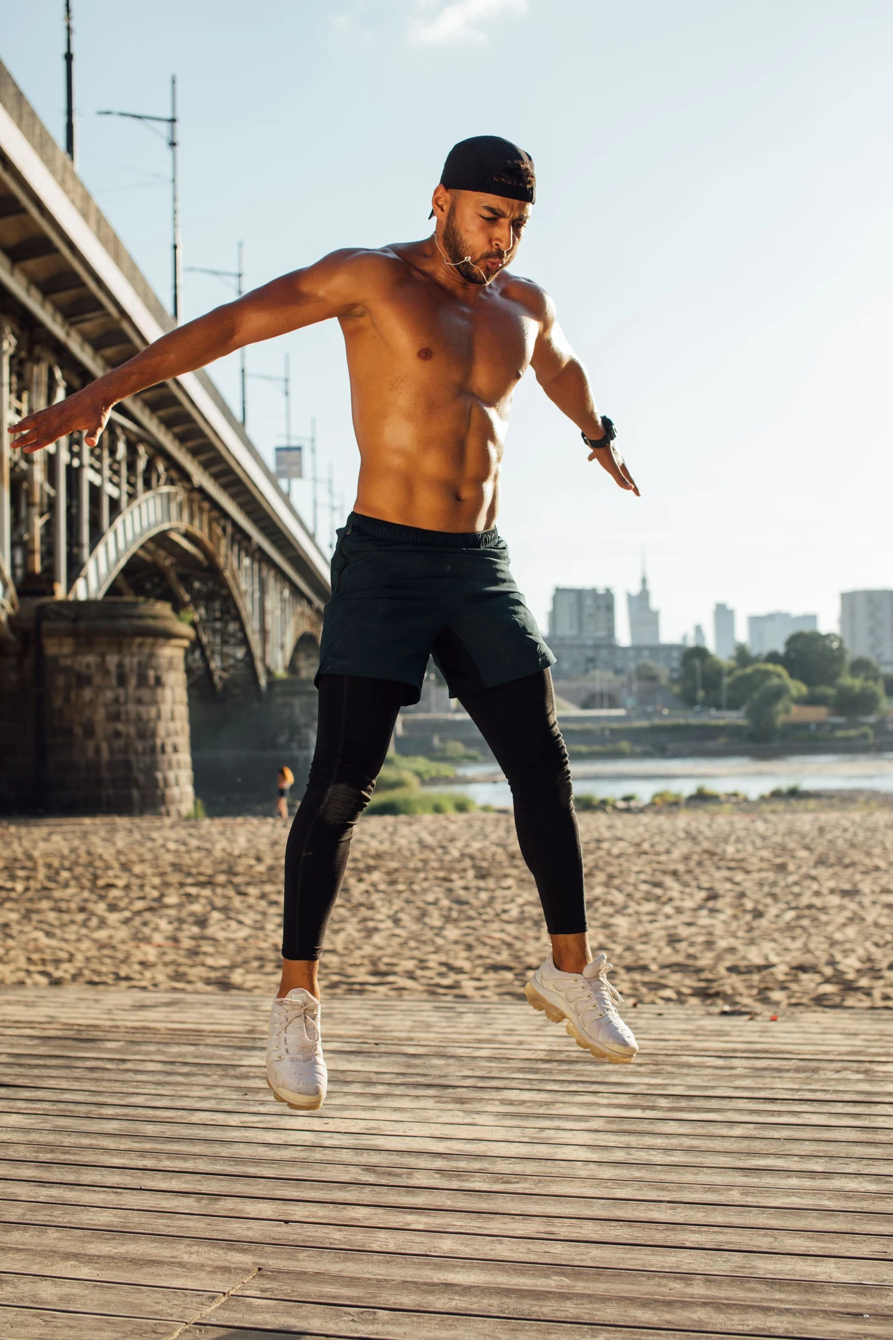 Man stretching in warm sunlight under a concrete colonnade