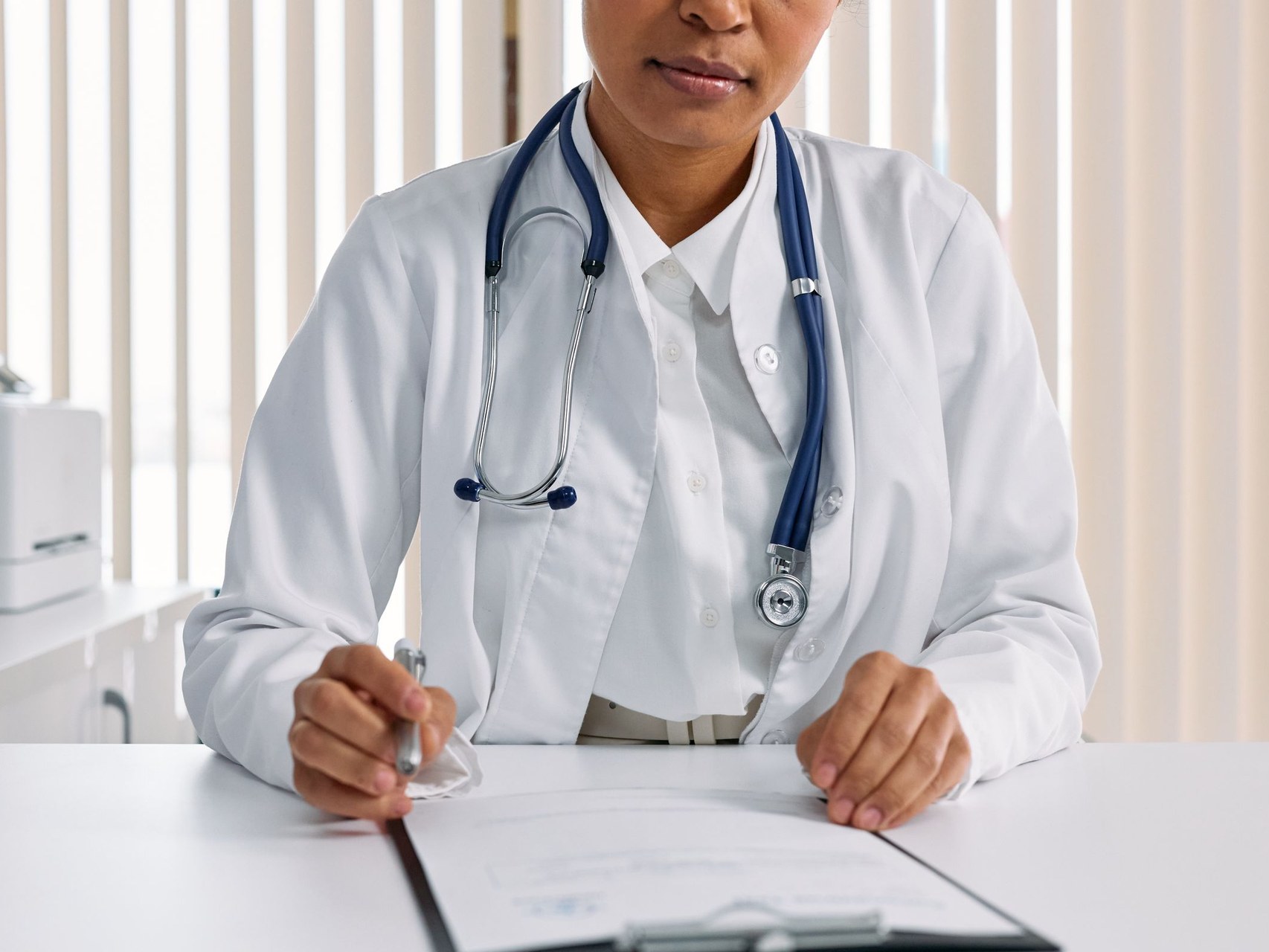 Board-certified clinician reviewing a patient case at her desk