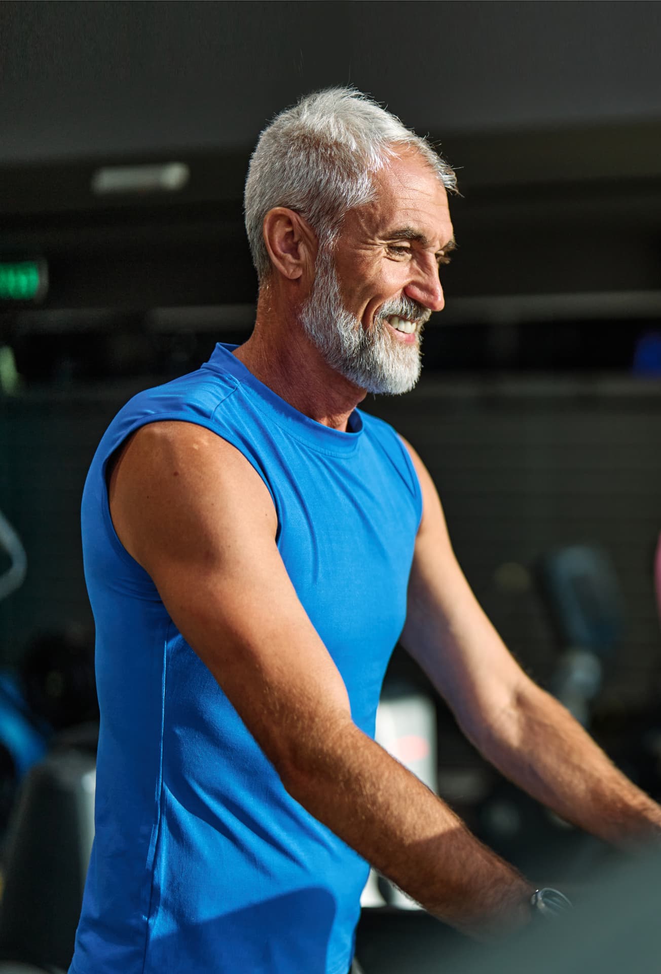 Older man in a blue tank top smiling during a workout