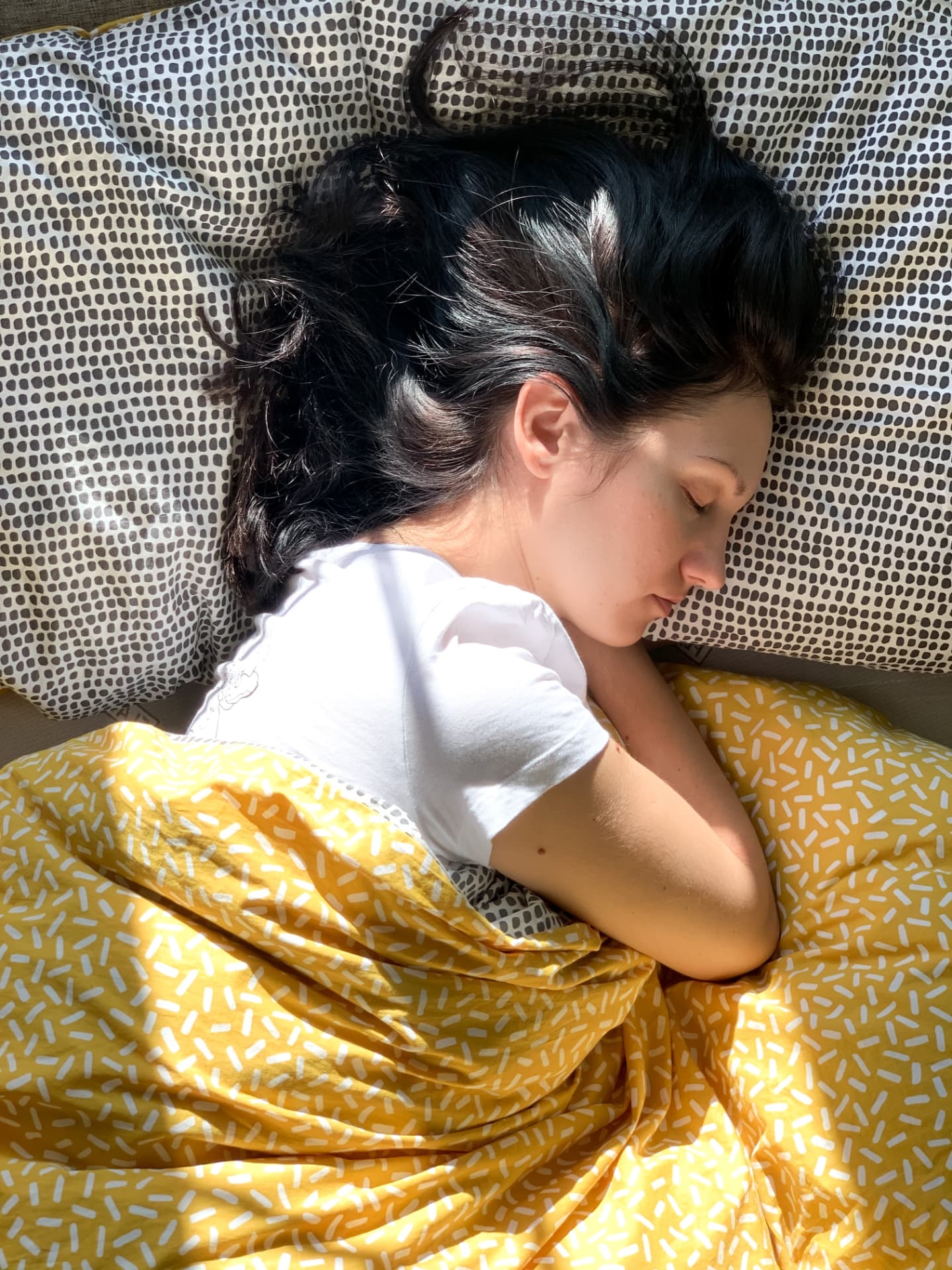 Woman sleeping peacefully in bed in bright morning sunlight