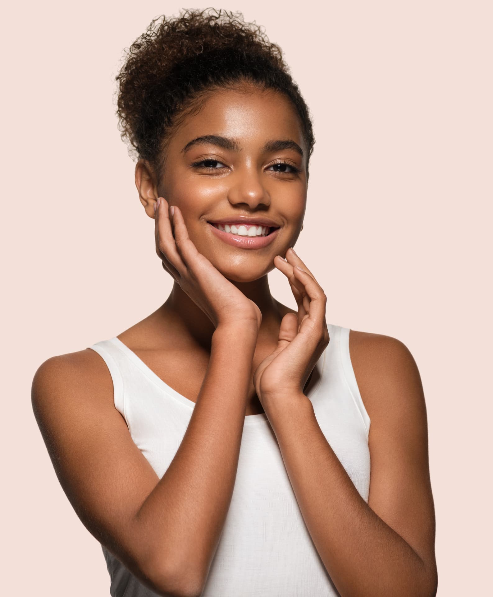 Smiling woman with clear, even skin resting her hands on her face