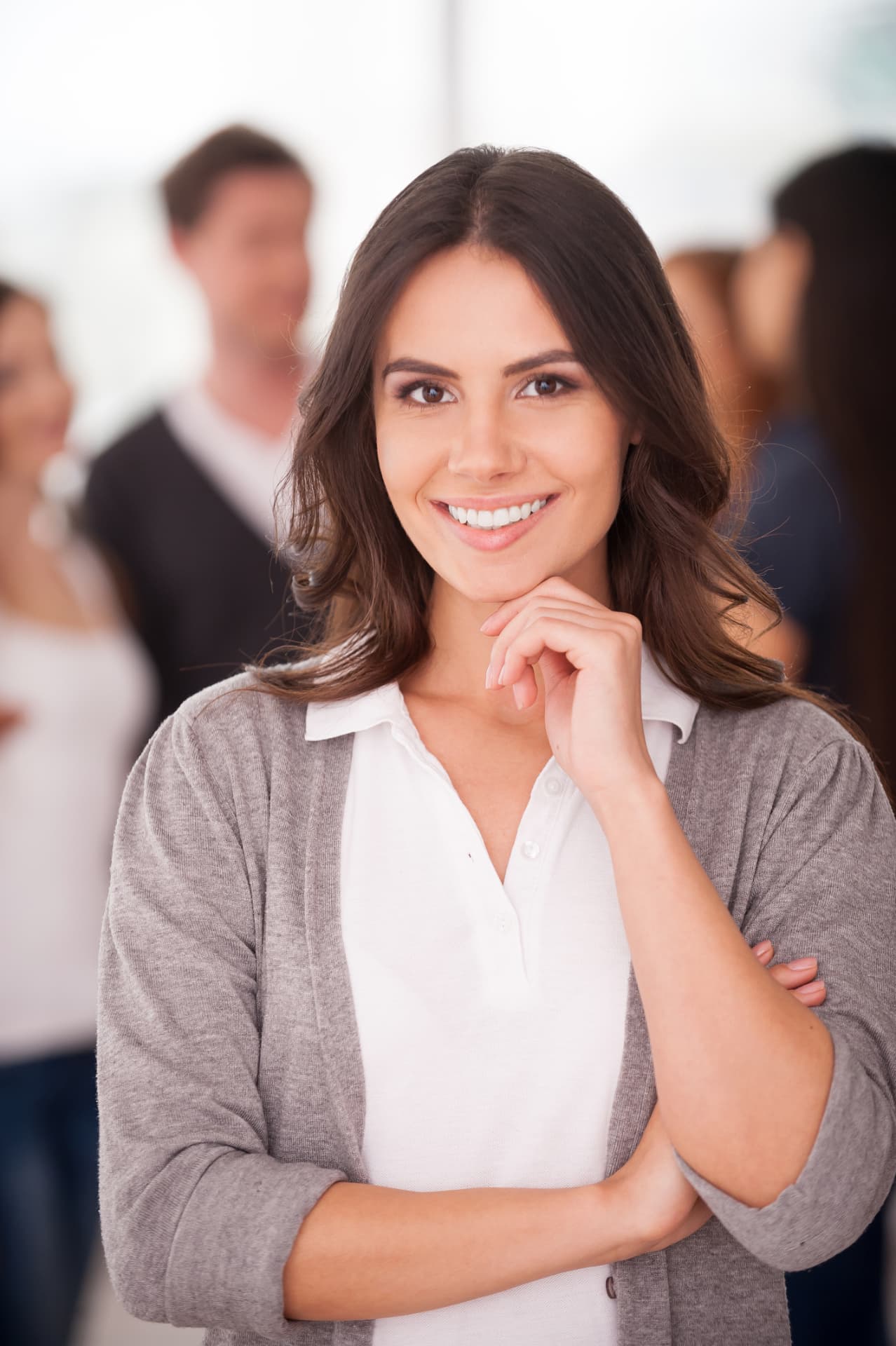 Smiling woman in a grey cardigan standing in a bright open workspace