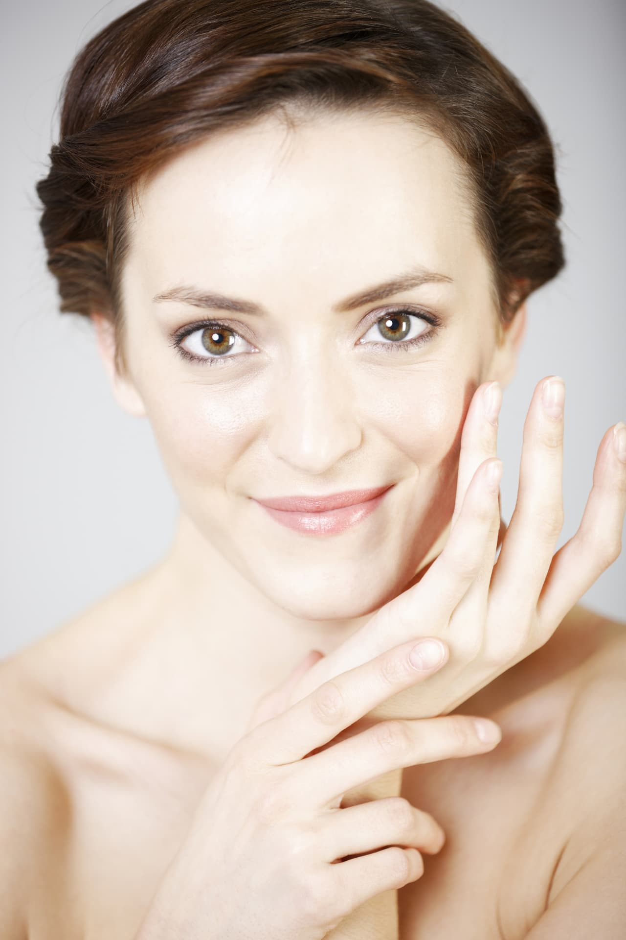 Elegant woman with bright, even skin resting her hand against her cheek
